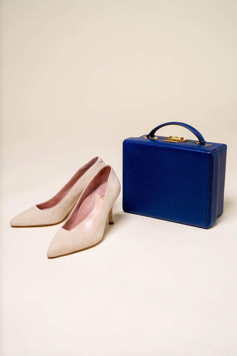 A pair of beige high heels next to a blue handbag.