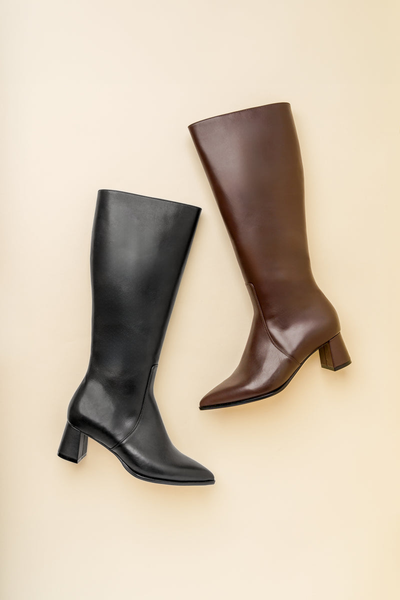 A pair of knee-high boots, one black and one brown, on a beige background.